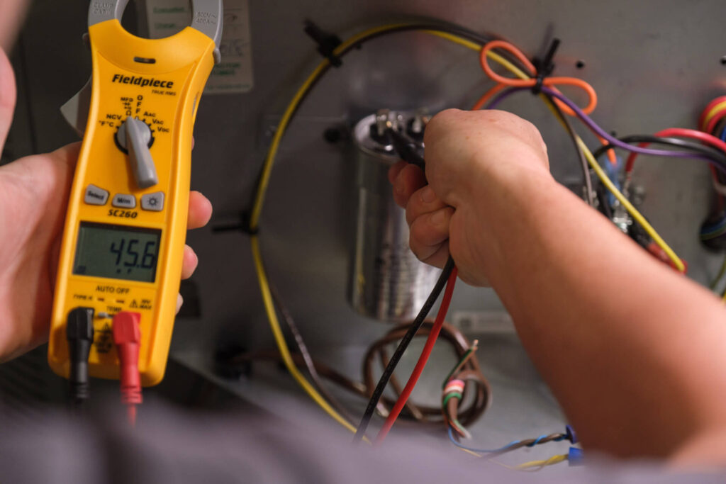 A Carolina Heating Service technician doing an electrical test - Carolina Heating Service Inc. A Carolina Heating Service technician doing an electrical test