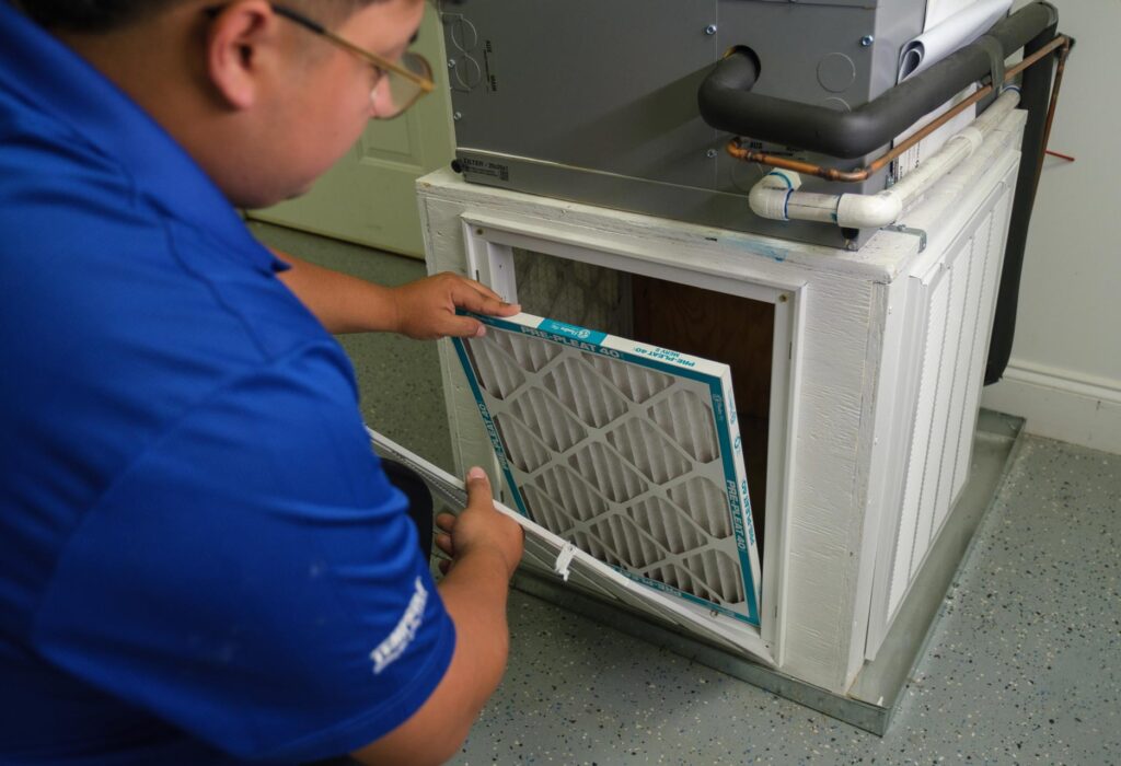 A technician replacing a filter on a gas furnace.