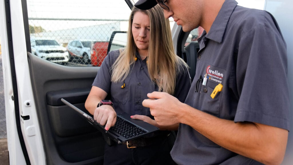 Two Carolina Heating Service technicians reviewing an item on a laptop - Carolina Heating Service Inc. Two Carolina Heating Service technicians reviewing an item on a laptop